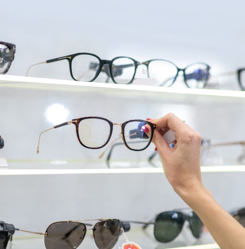 hand-choosing-eyeglasses-in-optical-store