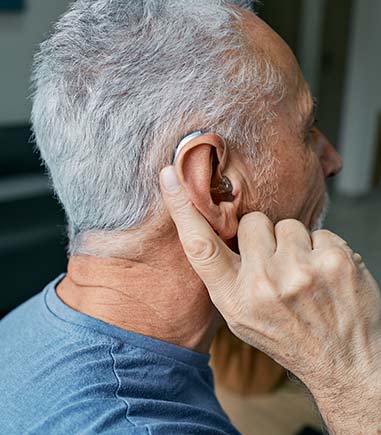 man-holding-finger-to-hearing-aid
